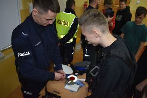 policjant pokazuje uczniom wyposażenie do służby