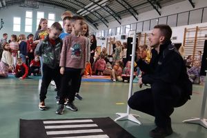 policjant uczy dzieci pokonywać jezdnię