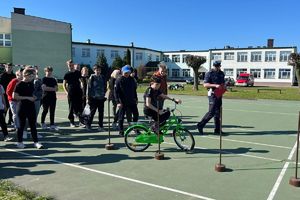 uczeń pokonuje rowerowy tor, policjant czuwa nad prawidłowością przejazdu