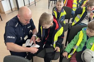 policjant pomaga chłopcu zrobić odbitki linii papilarnych