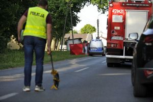 technik kryminalistyki , wóz strażacki, pracujący policjanci w tle