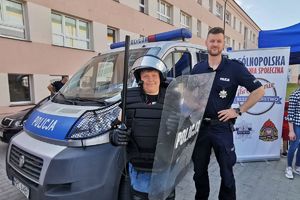 policjant przy radiowozie pozuje z chłopcem w stroju szturmowym