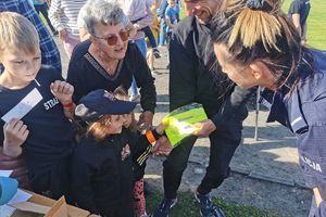 policjantka wręcza dzieciom szelki odblaskowe