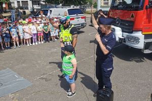 policjanci z chłopcem pokazują jak bezpiecznie przechodzić przez jezdnię