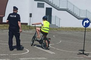 policjant sprawdza poprawność przejazdu dziecka na rowerze