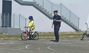 policjant sprawdza poprawność przejazdu dziecka na rowerze