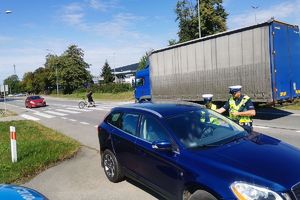 policjanci kontrolują pojazd, w tle pojazdy przed przejściem, na przejściu mężczyzna z rowerem