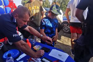 policjant pokazuje chłopcu jak zdjąć odbitki linii papilarnych