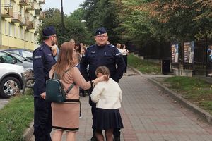 policjanci rozmawiają z mamą odprowadzającą dziecko do szkoły