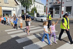 dzieci z policjantami przechodzą przez jezdnię