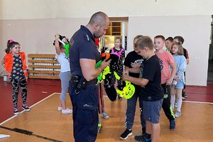 policjant podaje dzieciom odblaskowe zawwieszki