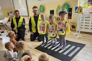 policjanci i dzieci w kamizelkach odblaskowych