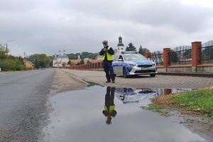 policjant mierzy prędkość, widać duże kałuże