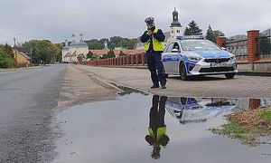 policjant mierzy prędkość, widać duże kałuże