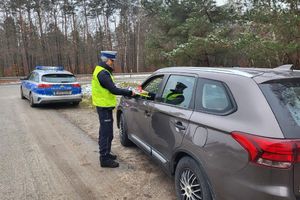 policjant wręcza kierowcy ulotki i opaskę odblaskową