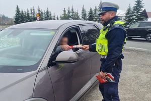 policjant wręcza kierowcy ulotki i opaskę odblaskową