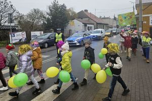 dzieci z kolorowymi balonami przechodzą przez pasy