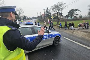 policjant zabezpieczający pochód macha do dzieci
