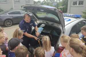 policjant pokazuje dzieciom kolcztkę drogową