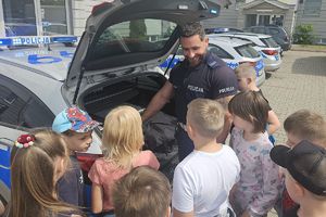 policjant przy radiowozie rozmawia z dziećmi