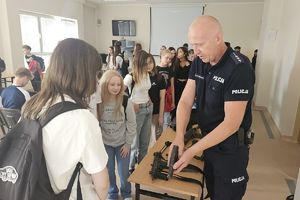 policjant pokazuje przybyłym broń