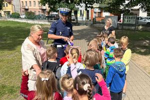 policjant rozdaje dzieciom opaski odblaskowe