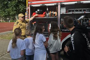 strażak pokazuje dzieciom wyposażenie pojazdu ratowniczego