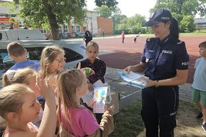 policjantka rozdaje dzieciom książeczki profilaktyczne