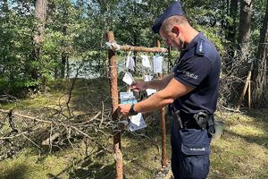 policjant wiesza ogłoszenie o konkursie