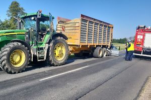 ciągnik rolniczy z przyczepą, obok widać policjantów wykonujących czunności