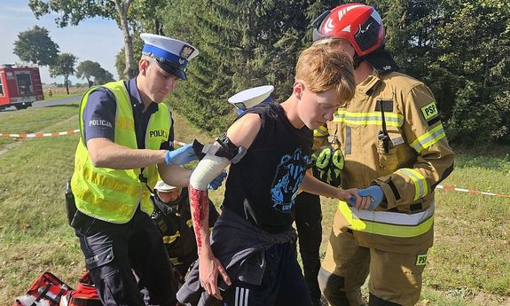 policjant i strażak pomagają poszkodowanemu