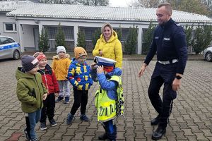 policjant z chłopcem w kamizelce odblaskowej i policyjnej czapce