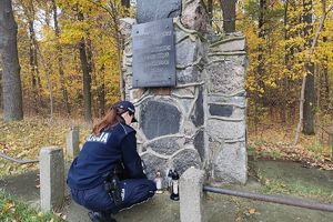 policjantka stawia znicz przy obelisku