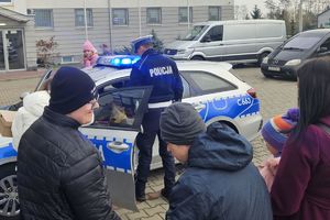 policjant ruchu drogowego pokazuje dzieciom radiowóz