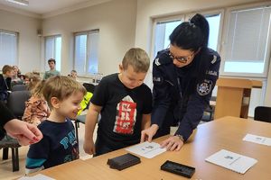 policjantka robi z dziećmi odbitki linii papilarnych