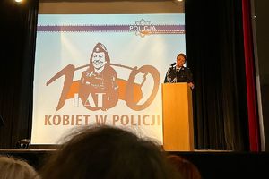 policjantka mówi do publiczności w tle logo 100-lecia kobiet w Policji