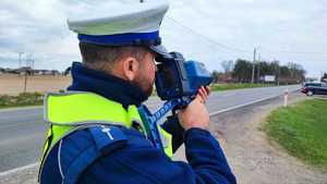 Policjant ruchu drogowego mierzy prędkość na drodze
