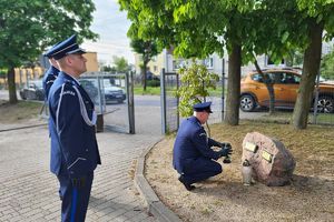 policjant stawia znicz przy pamiątkowym kamieniu