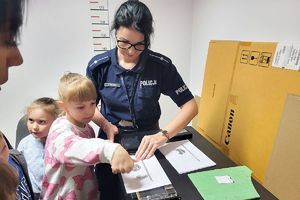 policjantka pomaga dziecku odwzorować swoją odbitkę palca