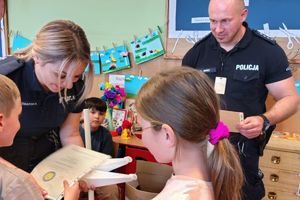 dzieci wręczają policjantom dyplom pamiatkowy