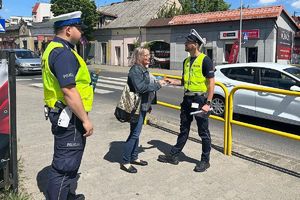 policjanci wręczają kobiecie ulotkę informacyjną