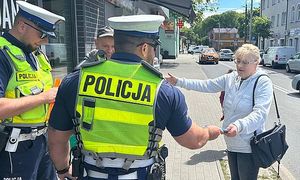 policjanci wręczają kobiecie ulotkę informacyjną