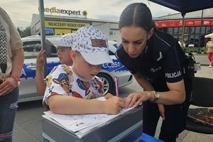 policjantka pomaga chłopcu rozwiązać łamigłówkę