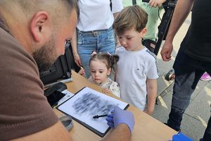 technik kryminalistyki ujawnia dla dzieci odbitki placów na kartce