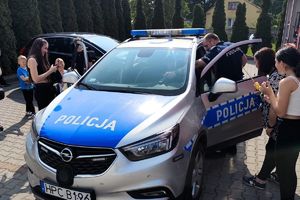 dzieci oglądają z policjantem radiowóz