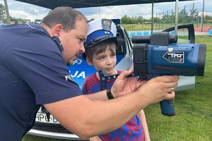 policjant ruchu drogowego pokazuje chłopcu fotoradar