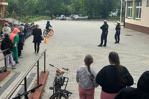 policjanci obserwują uczniów zdających egzamin praktyczny z jazdy rowerem