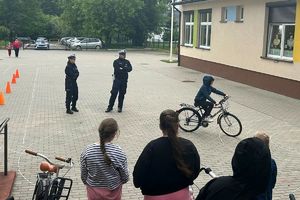policjanci obserwują uczniów zdających egzamin praktyczny z jazdy rowerem