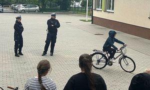uczeń jadący rowerem pod okiem policjantów