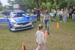 kobieta pokonuje slalom w alkogoglach w tle widać policjantów i innych uczestników pikniku